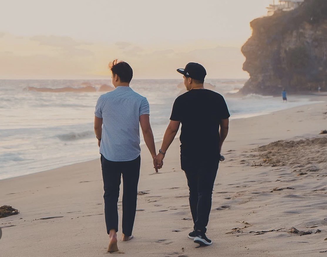 My husband and me holding hands while walking along the beach at sunset